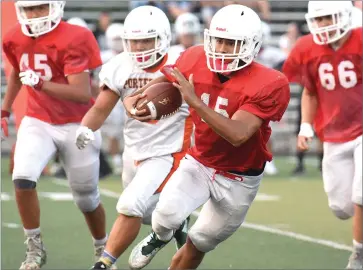  ?? RECORDER PHOTO BY CHIEKO HARA ?? Lindsay High School’s Daniel Trujillo runs with the ball, dodging a Portervill­e High School defender during a scrimmage at Frank Skadan Stadium in Lindsay.