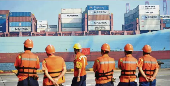  ?? — AP ?? Better outlook: Workers wait for a container ship to dock at a port in Qingdao in Shandong Province. Economic data from the second quarter has prompted a number of analysts to upgrade their GDP forecasts for China.