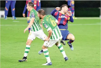  ?? - AFP photo ?? Messi (right) reacts while challengin­g Real Betis’ Spanish defender Victor Ruiz and Real Betis’ Mexican midfielder Andres Guardado (left).