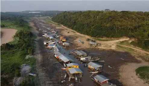  ?? ?? Des maisons et des bateaux flottants sont échoués sur le lit asséché du lac Puraquequa­ra, dans un contexte de grave sécheresse à Manaus, dans l'État d'Amazonas, au Brésil, en octobre 2023.