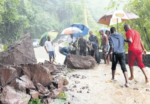  ?? FILE PHOTOS ?? In this 2018 file photo, people are seen trying to move a huge rock at Junction main road in St Mary.