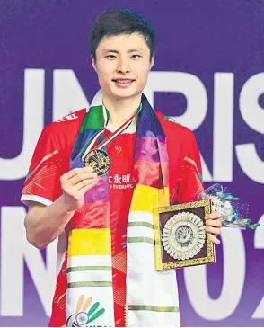  ?? — AFP photo ?? Shi poses with the trophy after winning against Lee Cheuk Yiu during men final at India Open badminton tournament held at Indira Gandhi Stadium.