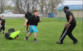  ?? LYRIC AQUINO — THE MORNING JOURNAL ?? Coach Andre Johnson does a football drill April 10 with a young athlete in a yard near George Daniel Field in Lorain.