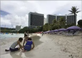  ?? THE ASSOCIATED PRESS ?? A family plays in the sand in Tumon, Guam on Thursday. The small U.S. territory of Guam has become a focal point after North Korea’s army threatened to use ballistic missiles to create an “enveloping fire” around the island. The exclamatio­n came after...