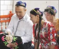  ?? ZHANG HONGCHI / XINHUA ?? Embroidere­r Kateerh Rahman teaches two women the traditiona­l craft in Hami, the Xinjiang Uygur autonomous region.