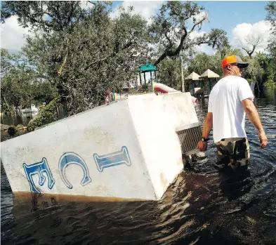  ?? BRIAN BLANCO / GETTY IMAGES ?? Waist-deep in flood water, Jason Coker drags an ice machine to dry land at the Peace River Campground in Arcadia, Fla. on Tuesday. Seven deaths in Florida have been blamed on Hurricane Irma.