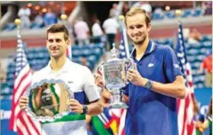  ?? AFP ?? Winner Russia’s Daniil Medvedev (right) and Serbia’s Novak Djokovic hold their trophies after the 2021 US Open Tennis tournament men’s final match on Sunday.