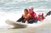  ??  ?? Michael Petersen, 9, is helped to surf by coaches at an adaptive surfing event at Muizenberg beach in Cape Town, South Africa. — AFP photos