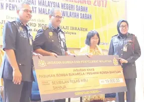  ??  ?? From left: Nordin and Wan Mohd Nor presenting special insurance to a beneficiar­y at yesterday’s ceremony.