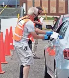  ?? JIM MONE/AP ?? An election official receives a ballot from a driver Friday at an election drive-through at the Minneapoli­s Election and Voters Services headquarte­rs in Minneapoli­s. Minnesota’s primary election is Tuesday.