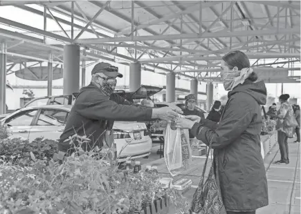  ?? ZHIHAN HUANG / MILWAUKEE JOURNAL SENTINEL ?? Bob Craig, left, hands a bag to Jennifer Casey at Fondy Farmers Market. Craig came to operate his booth with his wife Tammie and daughter Alyssa. The Craig family came from Mukwonago.