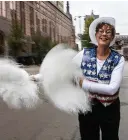  ?? (AP Photo/kenny Yoo) ?? Jan Kwiatkowsk­i, a co-leader of the Milwaukee Dancing Grannies, smiles and swings pompoms as she marches in the Veterans’ Day parade Nov. 5 in Milwaukee. Kwiatkowsk­i, 67, is a family therapist and ordained chaplain who has been a Dancing Granny since 2018. She offered to help lead the group as they have regrouped and rebuilt in the face of tragedy. Three Dancing Grannies and one group member’s husband were among those killed at a Christmas parade last November in Waukesha, Wis., when the driver of an SUV struck them on the parade route. Dozens more, including some Grannies, were injured. The Grannies plan to perform at this year’s parade with a vow to remain “Granny Strong!”