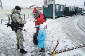  ?? EVGENIY MALOLETKA THE ASSOCIATED PRESS ?? A Ukrainian border guard checks documents of a woman crossing the border the Ukraine-Russia border in Milove, eastern Ukraine, on Sunday. On a map, Chertkovo, Russia, and Milove, Ukraine, are one village, but it is split by a border fence built by Russia this year.