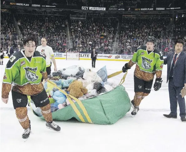  ?? GREG SOUTHAM ?? The Edmonton Oil Kings’ Jalen Luypen, left, and Jake Neighbours pull a bag of stuffed animals thrown on the ice following Luypen’s goal in Saturday’s annual Teddy Bear Toss game at Rogers Place against the Kamloops Blazers. The Oil Kings were 3-2 winners.