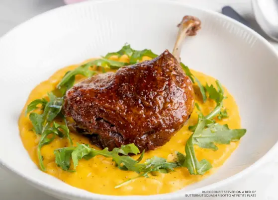  ?? ?? DUCK CONFIT SERVED ON A BED OF BUTTERNUT SQUASH RISOTTO AT PETITS PLATS