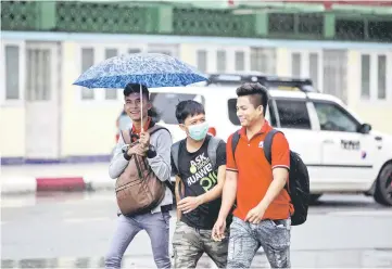  ??  ?? File photo shows a man wearing a face mask whilst walking with friends in Yangon. — AFP photo