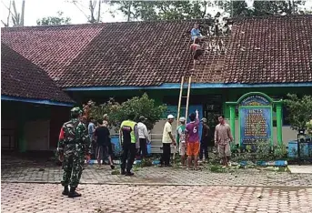  ?? SITI NURUL LAILIL M/JAWA POS RADAR TULUGAGUNG ?? GOTONG ROYONG: Warga bekerja bakti memperbaik­i gedung sekolah yang rusak akibat diterjang angin kencang kemarin.