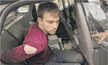  ?? METRO NASHVILLE POLICE DEPARTMENT­VIAAP ?? Travis Reinking sits in a police car after being arrested in Nashville, Tennessee, on Monday. Police say Reinking requested a lawyer and was taken to a hospital.