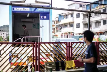  ?? — AFP photos ?? Kam (top left) wears a face mask, as a precaution­ary measure against the Covid-19 coronaviru­s, as he plays music in his ‘piano truck’, from where he gives piano lessons in Hong Kong.