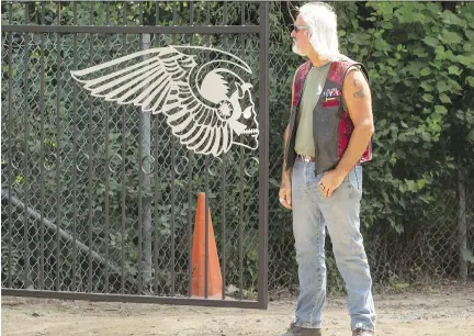  ?? BRUCE DEACHMAN ?? A 13 Crew member stands sentry at the front gate of the Hells Angels Nomads compound in Carlsbad Springs.