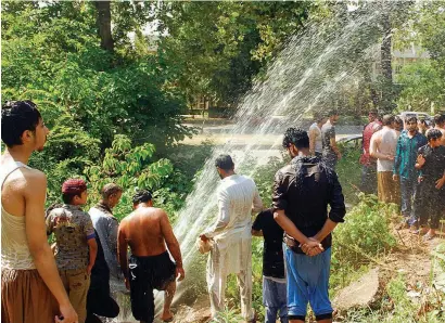  ?? — APP ?? People enjoying a shower through a leaked pipeline to get relief from the sizzling heat of summer.