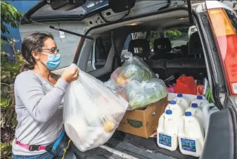  ?? Nick Otto / Special to The Chronicle ?? Mayela Gutknecht, a nurse with the San Francisco Department of Public Health, prepares to deliver groceries from the Mission Food Hub to families in need. She remains unvaccinat­ed.