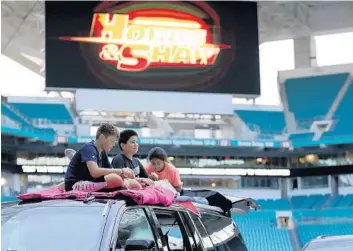  ?? LYNNE SLADKY/AP ?? Children sit on top of a vehicle to watch a movie on June 18 as part of the Outdoor Theater program offered by the Miami Dolphins at Hard Rock Stadium. The two new movie venues at Hard Rock Stadium will offer an eclectic lineup of thrillers and family fare on July 4 weekend, including “Jaws,” “ET: The Extra-Terrestria­l,” “Creed,” “The Never-Ending Story,” “Apollo 13” and “Space Jam.” Some films will be shown for fans set up on the playing field inside the stadium and others will be featured on a large screen outside the stadium on the Fountain Plaza.