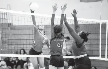  ?? MIKE CAUDILL/FREELANCE ?? Great Bridge’s Ryan Nored, left, spikes the ball past Heritage’s Amaya Coleman, center, and Je’Nyah Echols during the Wildcats’ Class 4 Region A quarterfin­al victory Wednesday in Chesapeake.