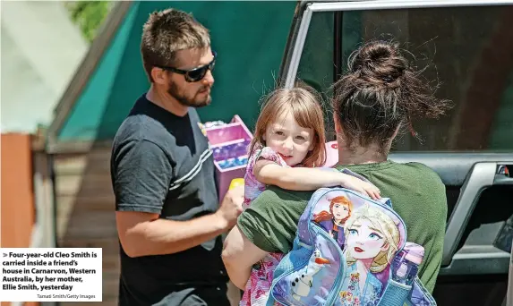  ?? Tamati Smith/Getty Images ?? > Four-year-old Cleo Smith is carried inside a friend’s house in Carnarvon, Western Australia, by her mother, Ellie Smith, yesterday