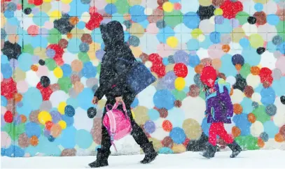  ?? Picture: Reuters ?? A woman and child walk through a winter snow storm in Boston, Massachuse­tts.