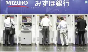  ?? — Reuters ?? People use the ATM machines of Mizuho Financial Group in Tokyo, Japan.