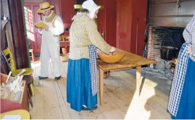  ?? PHOTOS BY TRACEE HERBAUGH VIA THE ASSOCIATED PRESS ?? People dressed in period costumes prepare dinner in the “Boarding with the Bixbys” program at Old Sturbridge Village in Sturbridge, Mass. The process of preparing food generally took several hours in the early 19th century. In the evenings, families...