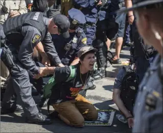  ?? JABIN BOTSFORD, THE WASHINGTON POST ?? Officers arrest protesters after a demonstrat­or set an American flag on fire at the main entrance of the Quicken Loans Arena on the third day of the Republican National Convention in Cleveland on Wednesday.