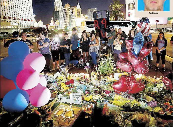  ??  ?? People gather at a makeshift memorial in the middle of Las Vegas Boulevard following the mass shooting at a concert area this week. REUTERS