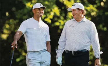  ?? CURTIS COMPTON / CCOMPTON@AJC.COM ?? Tiger Woods and Phil Mickelson have a laugh on the 11th tee while playing a practice round for the Masters at Augusta National Golf Club in April.