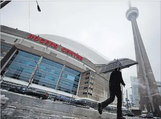  ?? COLE BURSTON THE CANADIAN PRESS ?? A man walks by the Rogers Centre as reports of falling ice from the CN Tower sparked a closure of parts of the area in Toronto on Monday.