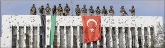  ?? UGUR CAN / DHA VIA AP ?? Turkish soldiers (right) and Turkey-backed opposition fighters stand atop a building next to their flags in the Syrian town of Ras al Ayn in northeaste­rn Syria on Wednesday.