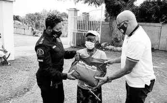  ?? CONTRIBUTE­D ?? Keith Duncan (right), president of the Private Sector Organisati­on of Jamaica and Stephanie Lindsay of the Jamaica Constabula­ry Force present a food package to a resident of Bull Bay in St Andrew.