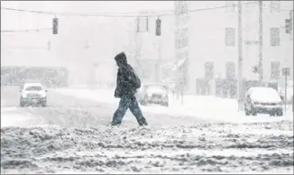  ?? ChrIS SteWArt / DAyton DAILy neWS ?? DAYTON, OHIO: A pedestrian walks on a snow-covered road during a blizzard Wednesday. About two dozen counties in Ohio and Indiana issued snow emergency travel alerts.
