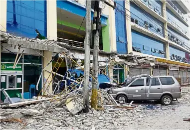  ?? — Reuters ?? Down to rubble: A car covered in debris from a damaged building after an earthquake hit Surigao city, southern Philippine­s.