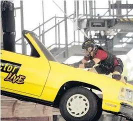  ?? ORLANDO SENTINEL FILE ?? Former Orlando Sentinel reporter Eric Michaels crawls across the hood of a car suspended 25 feet in the air at “Fear Factor Live” in 2005.