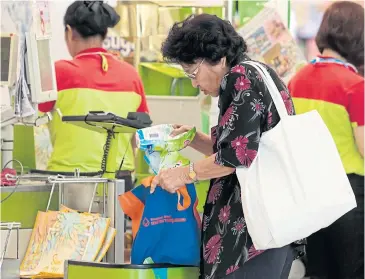  ?? PATIPAT JANTHONG ?? A shopper puts purchased items into a cloth bag because no plastic bags were offered yesterday at Big C.