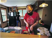  ??  ?? Nate Thames slices freshly baked bread while preparing lunch with his wife Elizabeth, rear, after a morning working on their Vermont property.