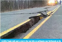  ?? —AFP ?? ALASKA: People walk past a crack in the road after an earthquake near Northwoods on the Kenai Spur Highway in Kenai, Alaska.