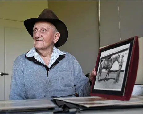  ?? Photo: Bev Lacey ?? GREAT MEMORIES: Former Toowoomba horse trainer and farrier Vince Nugent looking back this week at some of his racing memorabili­a including a photo of himself with Dream Court.