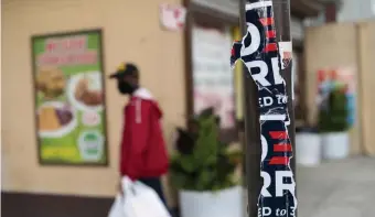  ?? Getty images ?? ALL OVER BUT THE ASCERTAINM­ENT: A man carries groceries past tattered ‘Biden Harris’ campaign signs Tuesday in Philadelph­ia. For Joe Biden to officially become president-elect, the General Services Administra­tion must ascertain him as the ‘apparent successful candidate.’