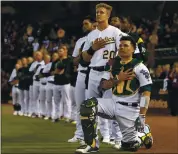  ?? NHAT V. MEYER — STAFF PHOTOGRAPH­ER ?? Athletics catcher Bruce Maxwell kneels next to Mark Canha (20) during the national anthem before a 2017 game.