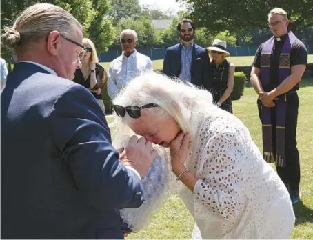  ?? ANTONIO PEREZ/CHICAGO TRIBUNE PHOTOS ?? Lea Minalga, a longtime anti-drug and family support advocate, weeps with the urn containing the ashes of her son, Justin Pearlman, at his burial at Union Cemetery in St. Charles on July 21. Pearlman died last year of a fentanyl overdose after a long period of sobriety.