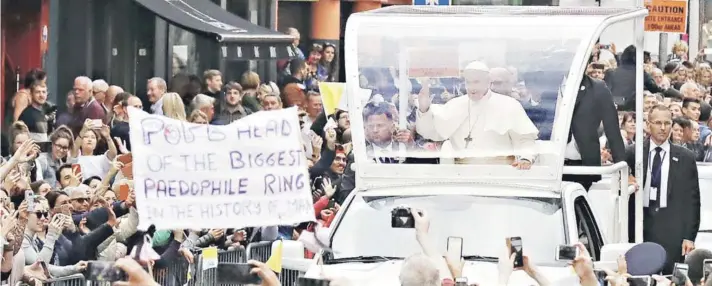  ??  ?? ► El Papa Francisco tras visitar la Procatedra­l de Santa María, en Dublín, junto a un lienzo de un manifestan­te que se expresa contra la pedofilia en la Iglesia.