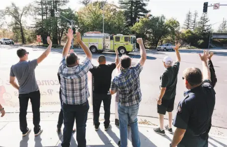  ?? Michael Short / Special to The Chronicle ?? Windsor city officials wave to a passing fire truck as they greet residents returning to their homes after evacuation orders were lifted for the town. “Those firefighte­rs worked so hard . ... They saved every home in town,” said Mayor Dominic Foppoli.